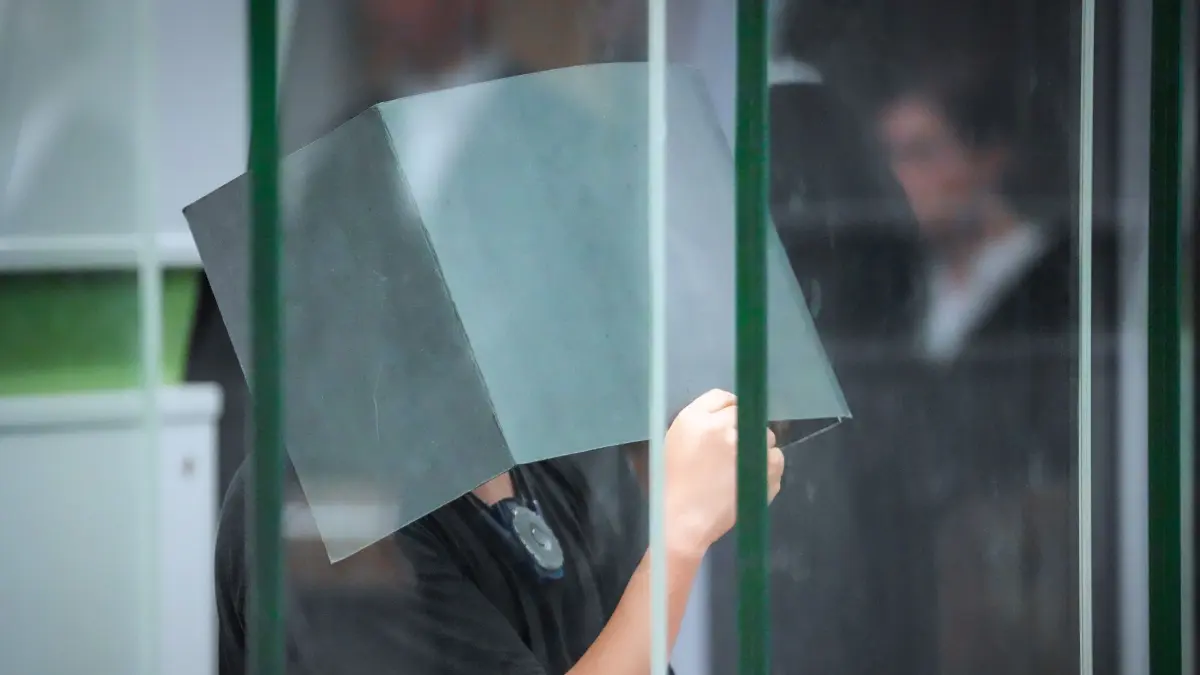 Prozess gegen 32-Jährigen wegen Vergewaltigungen: ARCHIV - 08.07.2026, Berlin: Der Angeklagte hält sich zum Beginn des Prozesstages im Kriminalgericht Moabit einen Aktenordner vors Gesicht. Der 32-Jährige hat laut Urteil eine Frau mehrfach im Schlaf missbraucht. (zu dpa: «Frauen betäubt, vergewaltigt und gefilmt? Berliner angeklagt») Foto: Soeren Stache/dpa +++ dpa-Bildfunk +++