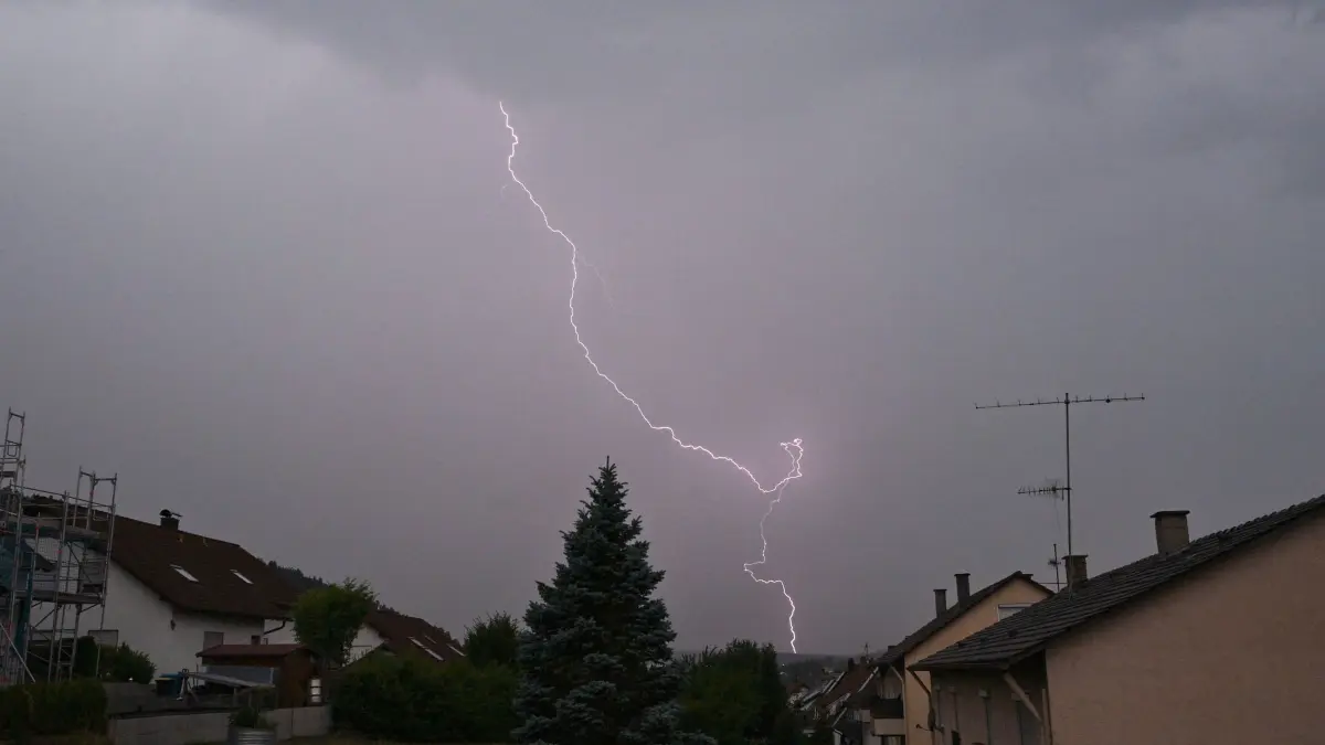 Wetter in Baden-Württemberg: 14.07.2026, Baden-Württemberg, Rottweil: Blitze und dunkle Wolken sind in einem Wohngebiet bei Rottweil zu sehen. (Standbild aus einem Video). Foto: Silas Stein/dpa +++ dpa-Bildfunk +++
