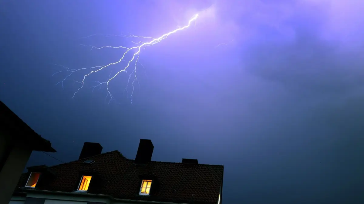 Blitze über einem Wohnhaus: ARCHIV - 20.07.2022, Bayern, Würzburg: Blitze über einem Wohnhaus während eines Gewitters. (zu dpa: «Blitzschlag verletzt Frau mit Smartphone») Foto: Karl-Josef Hildenbrand/dpa/dpa-tmn +++ dpa-Bildfunk +++