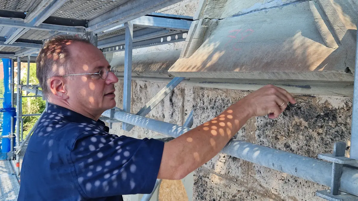 Wie lebt und arbeitet es sich auf einer Millionen-Baustelle? Pfarrer Christoph Kirn zeigt auf dem 44 Meter hohen Gerüst die Wetterschäden an der Fassade der Johanneskirche.