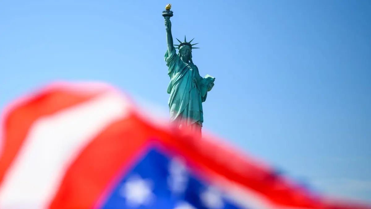 WM 2026 - New York: 17.07.2026, USA, New York: Die Fahne der USA weht vor der Freiheitsstatue. Foto: Tom Weller/dpa +++ dpa-Bildfunk +++