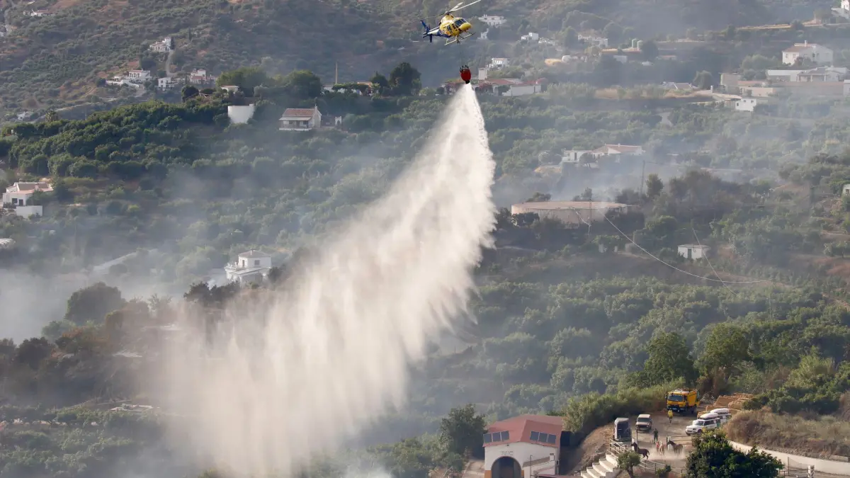 Waldbrände in Spanien: 17.07.2026, Spanien, Málaga: Ein Löschhubschrauber ist während eines Waldbrandes im Einsatz. Der Waldbrand, der an diesem Freitag in der Gemeinde Archez ausgebrochen ist, hat zur vorsorglichen Evakuierung von Siedlungen geführt. Foto: Álex Zea/EUROPA PRESS/dpa +++ dpa-Bildfunk +++
