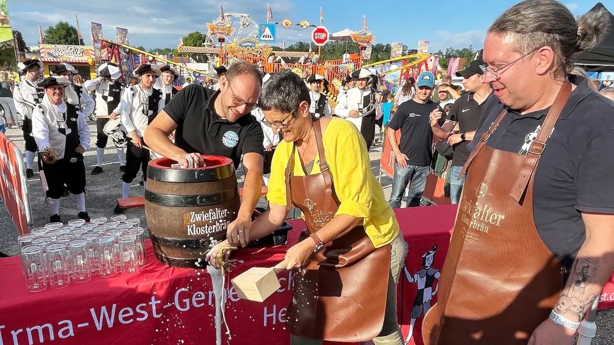 Beim Bieranstich auf dem Hechinger Festplatz am Freitagabend: Premiere für die Erste Beigeordnete Dorothee Müllges „am Hammer“, unterstützt von Alexander Straub von der Getränkefirma HeimFest. Rechts im Bild: Stefan Walter.