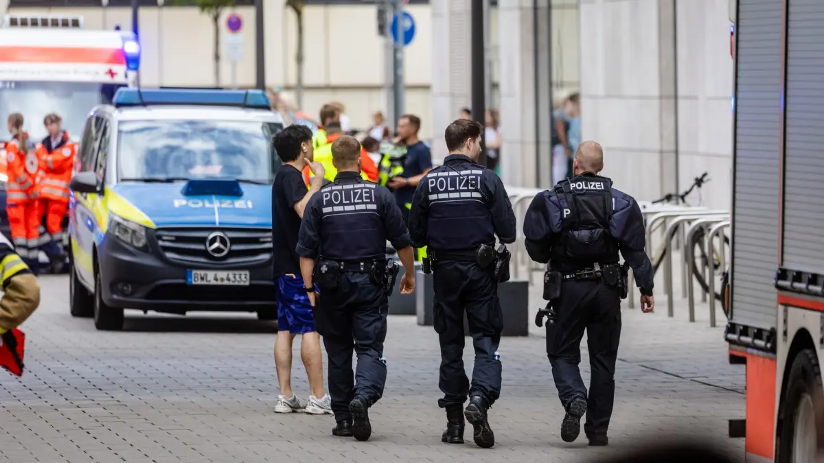 Polizeieinsatz in Stuttgarter Einkaufszentrum: 23.07.2025, Baden-Württemberg, Stuttgart: Polizisten gehen bei einem größeren Polizeieinsatz vor einem Einkaufszentrum in der Innenstadt. In dem Einkaufszentrum ist eine Person schwer verletzt worden. Nach Auskunft der Polizei ist der unbekannte Täter flüchtig und wird gesucht. Foto: Christoph Schmidt/dpa +++ dpa-Bildfunk +++