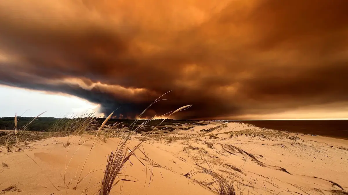 Waldbrand in Frankreich: 24.07.2026, Frankreich, Lacanau: Rauchwolken von den Waldbränden südöstlich des Badeortes Lacanau-Ocean (hinten, r) verdunkeln den Himmel, während sie über die Dünen am Nordstrand hinwegziehen. Foto: Jan Athmann/dpa +++ dpa-Bildfunk +++