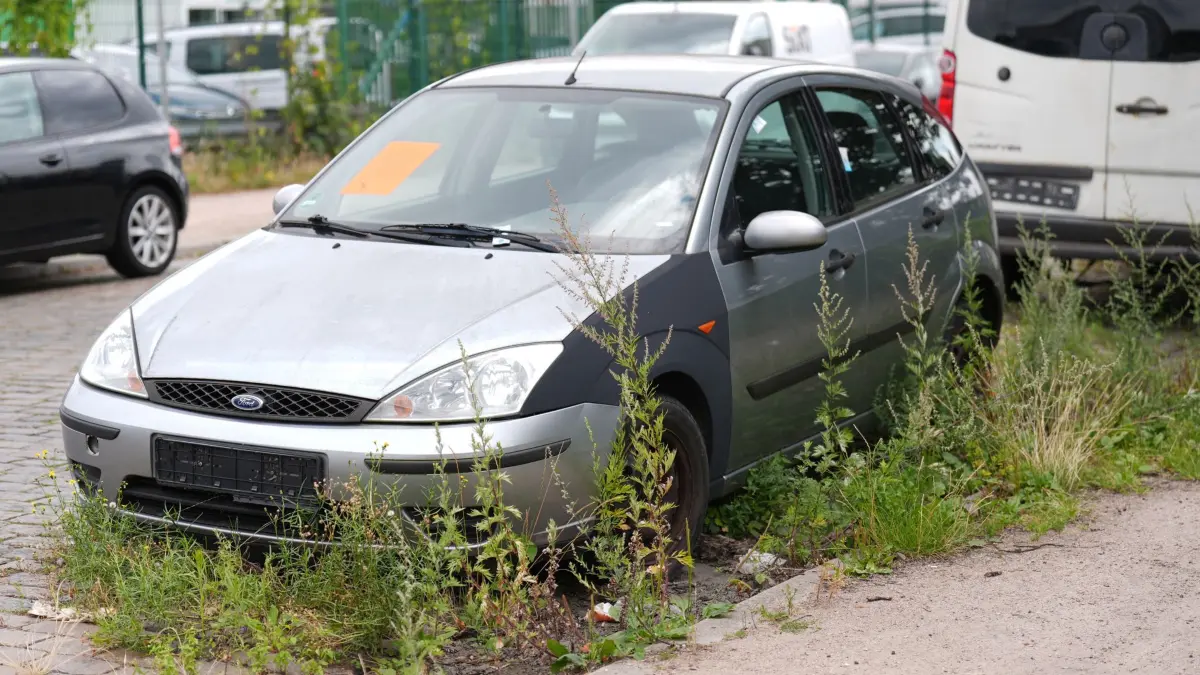 Illegal abgestelltes Schrottauto: 24.07.2026, Hamburg: Pflanzen wachsen um ein nicht mehr zugelassenes und unrechtmäßig abgestelltes Fahrzeug in einer Straße im Stadtteil Altona. Foto: Marcus Brandt/dpa +++ dpa-Bildfunk +++