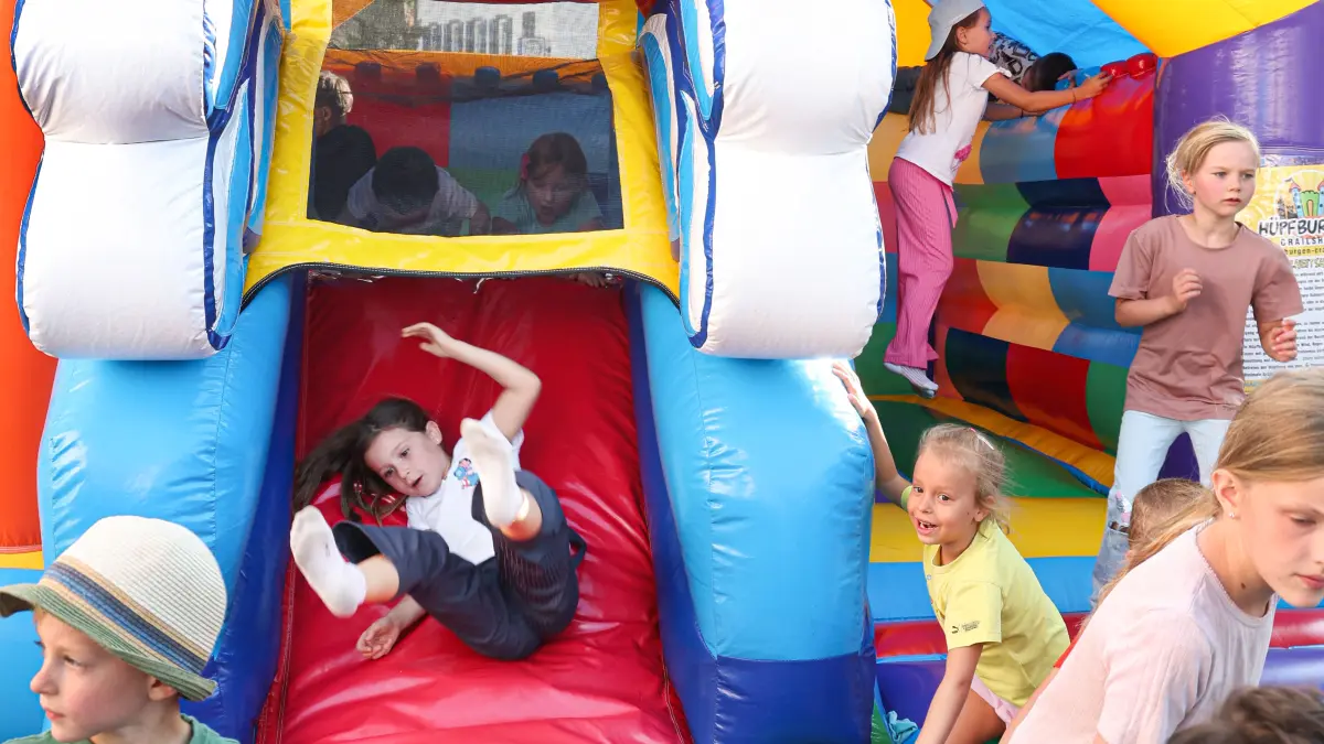 Kinder rutschen und toben auf der Hüpfburg.