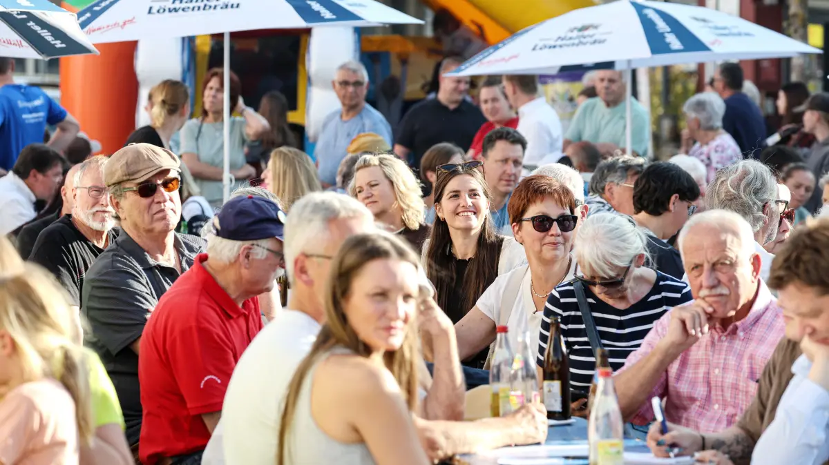 Vollbesetzt sind die Bänke auf dem Marktplatz in Braunsbach. Aufmerksam verfolgen die Besucherinnen und Besucher das Programm auf der Bühne mit Grußworten, Kindergarten-Malwettbewerb und Bürgermeister-Interview. Im Hintergrund stehen die Menschen am Stand des TSV Braunsbach für Essen und Getränke Schlange.