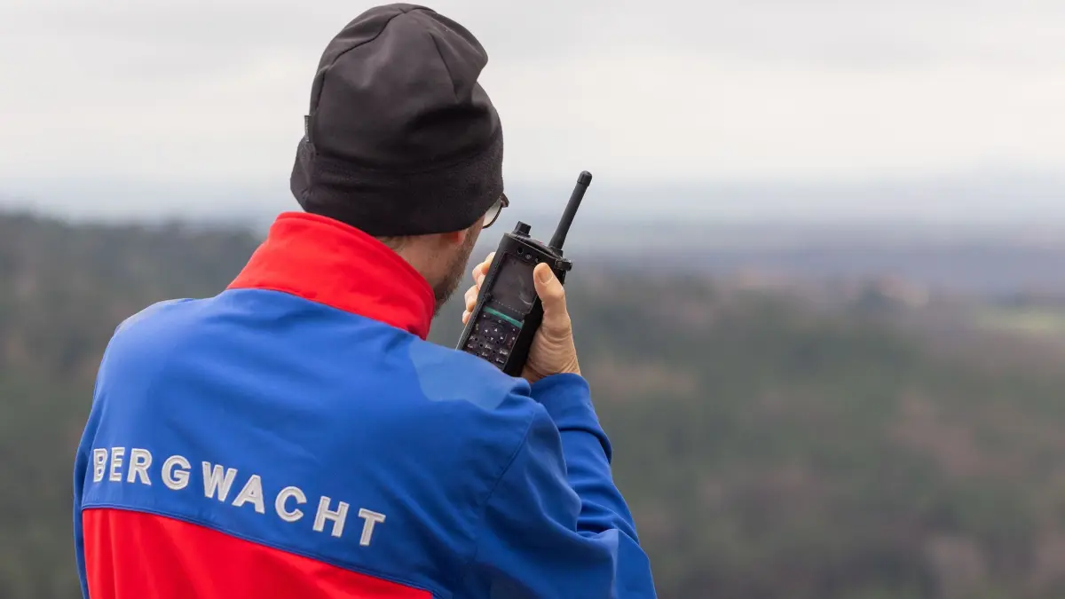 Großübung der Bergwacht des DRK: ARCHIV - 15.03.2026, Sachsen, Struppen: Ein Bergretter spricht während einer Übung der Bergwacht des Deutschen Roten Kreuzes (DRK) Dresden am Rauenstein in der Sächsischen Schweiz in sein Funkgerät. An mehreren Stationen trainieren die Bergretter verschiedene Hilfs- und Einsatztechniken für die Rettung von Personen. Diese reichen von der Kameraden- und Patientensicherung im absturzgefährdeten Gelände über die Rettung verunfallter Kletterer von Kletterfelsen bis zur Rettung aus Spalten mit umfangreichen Rettungshilfsmitteln. (zu dpa: «Bergwacht warnt vor Leichtsinn beim Wandern») Foto: Jürgen Lösel/dpa +++ dpa-Bildfunk +++