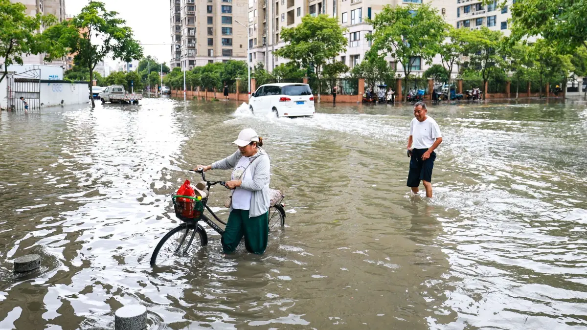 Taifun „Bavi“ - China: ARCHIV - 12.07.2026, China, Yueqing: Menschen gehen durch eine überflutete Straße in der Stadt in der ostchinesischen Provinz Zhejiang. Der Taifun «Bavi» ist in Richtung der chinesischen Ostküste gezogen. (zu dpa: «Geringe Schäden durch Naturkatastrophen im ersten Halbjahr») Foto: Jiang Han/XinHua/dpa +++ dpa-Bildfunk +++