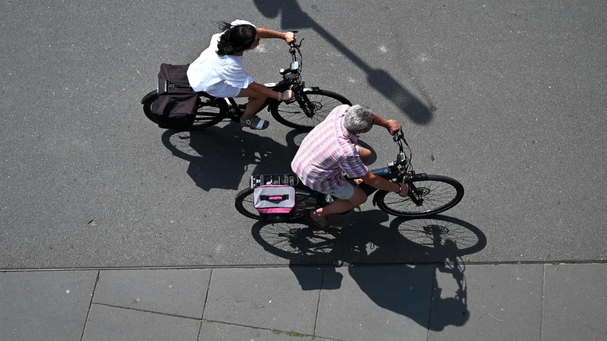 Wetter in Offenbach am Main: 31.07.2026, Hessen, Offenbach am Main: Eine Frau und ein Mann fahren am Offenbacher Mainufer mit dem Fahrrad in Richtung Frankfurt. Die Temperaturen steigen heute in Hessen nach Angaben des Deutschen Wetterdienstes gebietsweise auf 30 bis 34 Grad an. Foto: Jennifer Brückner/dpa +++ dpa-Bildfunk +++