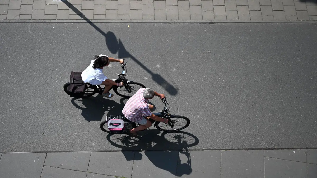 Wetter in Offenbach am Main: 31.07.2026, Hessen, Offenbach am Main: Eine Frau und ein Mann fahren am Offenbacher Mainufer mit dem Fahrrad in Richtung Frankfurt. Die Temperaturen steigen heute in Hessen nach Angaben des Deutschen Wetterdienstes gebietsweise auf 30 bis 34 Grad an. Foto: Jennifer Brückner/dpa +++ dpa-Bildfunk +++