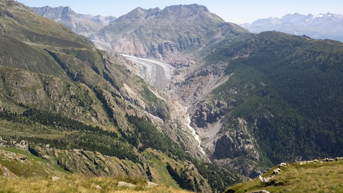 Hitze in der Schweiz: 28.07.2026, Schweiz, Bern: Blick auf die Alpen und die Gletscherzunge des Aletschgletschers vom Triembiel oberhalb des Dorfes Belalp (VS) am Dienstag, 28. Juli 2026. Nachdem die Schweiz in diesem heißen Sommer bereits von mehreren Hitzewellen heimgesucht wurde, suchen viele Menschen Abkühlung in den Höhenlagen, während die anhaltende Trockenheit und die hohen Temperaturen die Alpenregion weiterhin prägen. Foto: Anthony Anex/KEYSTONE/dpa +++ dpa-Bildfunk +++