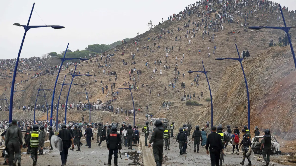 MOROCCO-SPAIN-MIGRATION: Members of Moroccan security forces gather at the site of clashes near Fnideq, on the Morocco-Spain border, on July 31, 2026. Thousands of migrants crossed overnight from Morocco into Spain's north Africa's Ceuta enclave, a police source said on July 31, adding that it was impossible to estimate how many people in total. A total of 18 people died while attempting to reach the Spanish enclave, the source said. (Photo by Abdel Majid BZIOUAT / AFP)