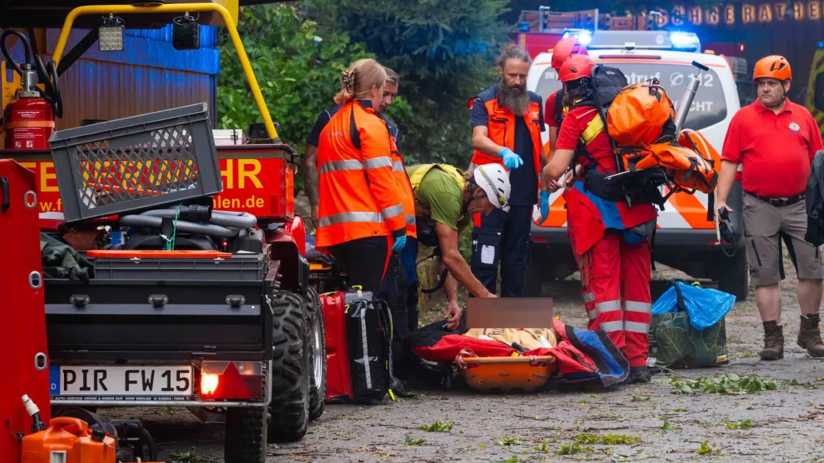 Mann von Baum erschlagen - Toter bei Unwetter in Sachsen: 31.07.2026, Sachsen, Rathen: Einsatzkräfte stehen im Bereich der Felsenbühne Rathen an einer Trage, auf der eine Person liegt. Bei einem Unwetter in Sachsen ist ein Mann ums Leben gekommen. Er sei in Rathen von einem umgestürzten Baum erschlagen worden, sagte ein Polizeisprecher. Außerdem gab es Verletzte. Foto: Jonas Schubert/xcitepress/dpa +++ dpa-Bildfunk +++