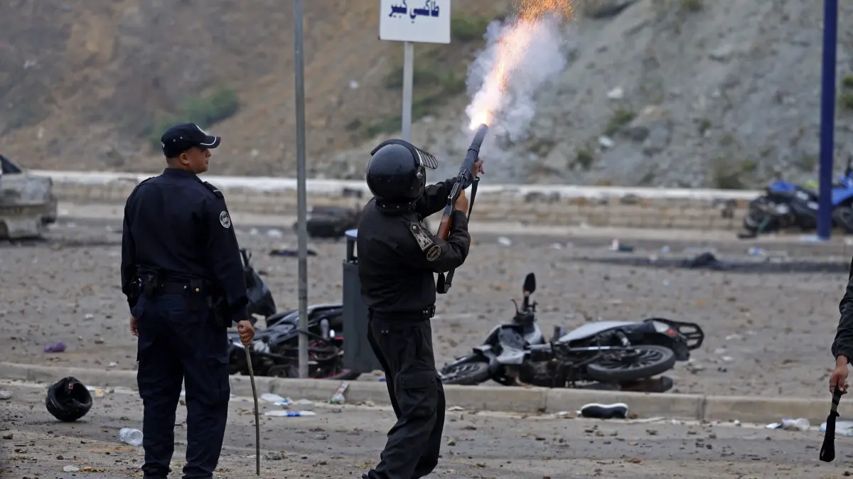 MOROCCO-SPAIN-MIGRATION: A member of Moroccan security forces fires a teargas shell to disperse the crowds at the site of clashes near Fnideq, on the Morocco-Spain border, on July 31, 2026. Thousands of migrants crossed overnight from Morocco into Spain's north Africa's Ceuta enclave, a police source said on July 31, adding that it was impossible to estimate how many people in total. A total of 18 people died while attempting to reach the Spanish enclave, the source said. (Photo by Abdel Majid BZIOUAT / AFP)