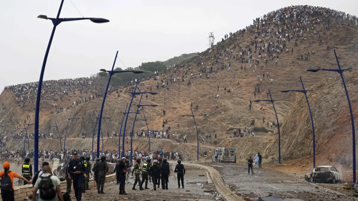 MOROCCO-SPAIN-MIGRATION: Members of Moroccan security forces gather at the site of clashes near Fnideq, on the Morocco-Spain border, on July 31, 2026. Thousands of migrants crossed overnight from Morocco into Spain's north Africa's Ceuta enclave, a police source said on July 31, adding that it was impossible to estimate how many people in total. A total of 18 people died while attempting to reach the Spanish enclave, the source said. (Photo by Abdel Majid BZIOUAT / AFP)