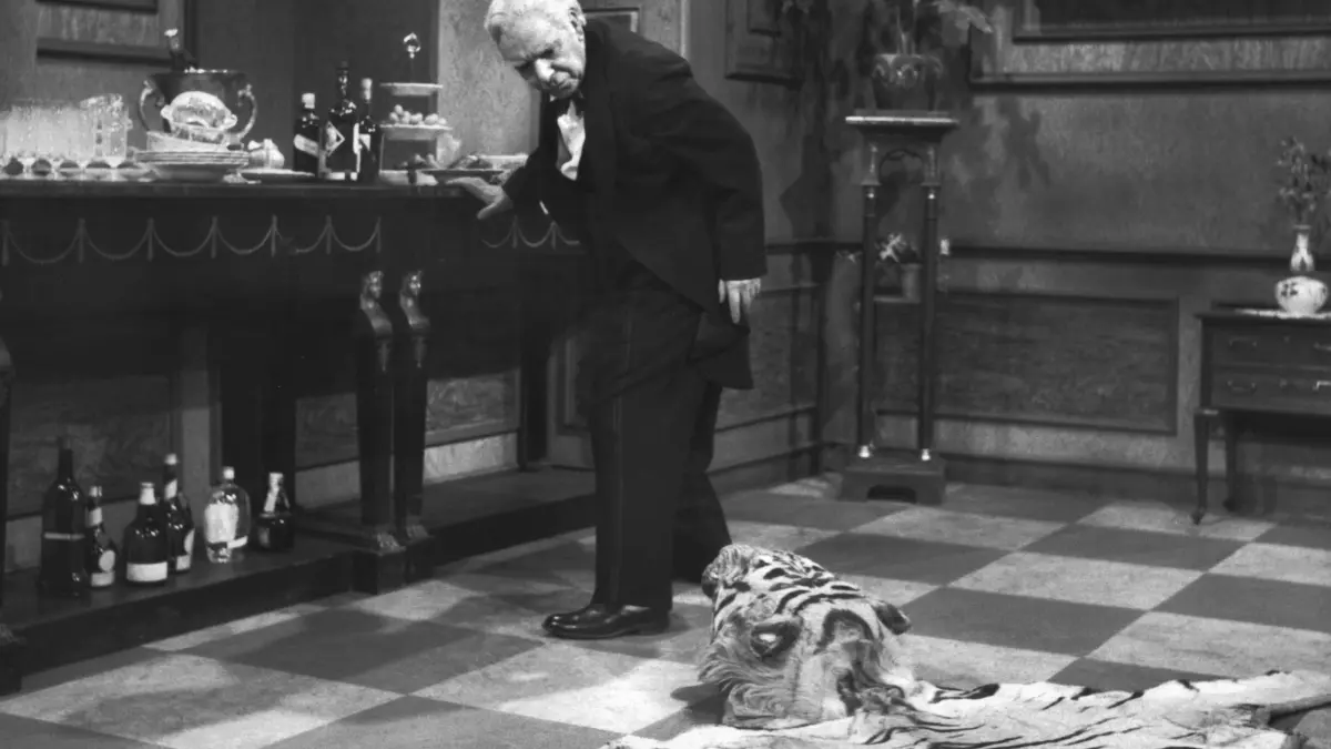 Butler James, 7859896 gespielt von Freddie Frinton, schaut mißbilligend zu dem auf dem Boden liegenden Tigerfell, das eine ständige Stolperfalle auf dem Weg von und zur Anrichte ist. Der Sketch "Der neunzigste Geburtstag" oder "Dinner for one" hat sich seit der Erstsendung am 8. März 1963 im deutschen Fernsehen fest etabliert und ist seit Jahren ein "Silvester-Standard" in den Dritten Programmen (undatiertes Szenenfoto). Foto: NDR dpa/lno (zu dpa-Korr "Fernsehen zum Jahreswechsel" vom 26.12.) +++ dpa-Bildfunk +++