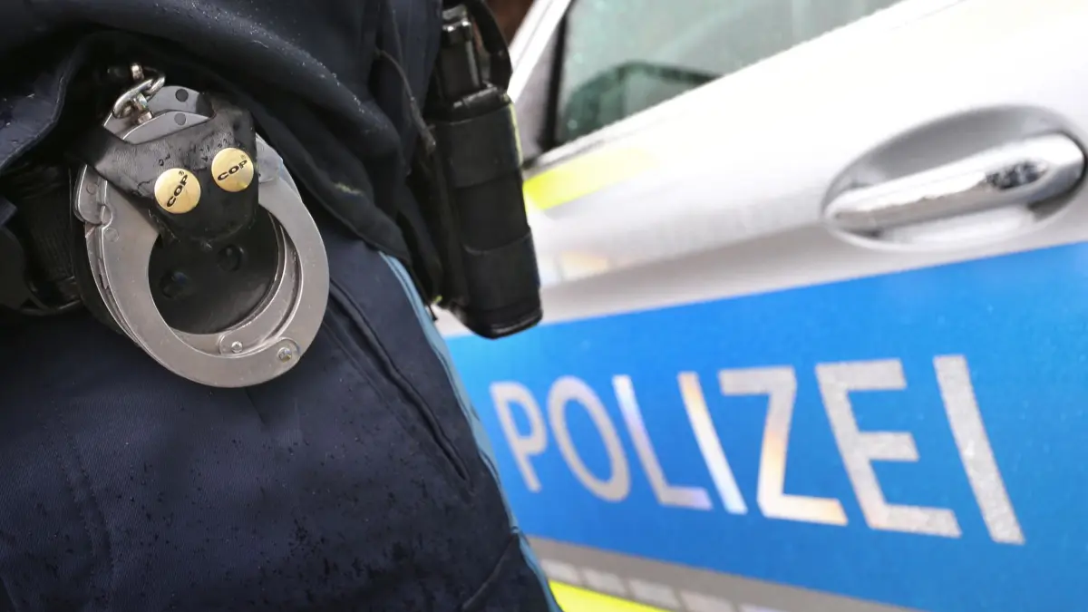 Polizei: ARCHIV - 15.03.2019, Bayern, Kempten: Ein Polizist mit Handschellen und einer Pistole am Gürtel steht vor einem Streifenwagen. (zu dpa: «34-Jähriger stirbt nach Festnahme in München») Foto: Karl-Josef Hildenbrand/dpa +++ dpa-Bildfunk +++