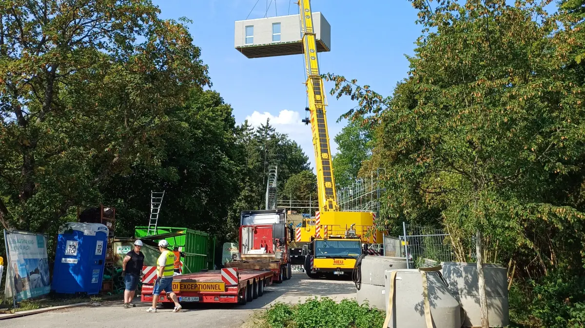 Ein Kran hievt die Module für den Holzbau auf den Parkplatz am Herbstenhof