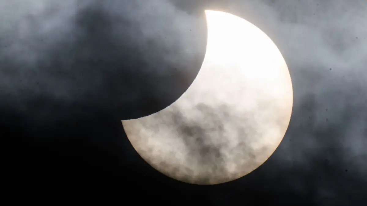 Partielle Sonnenfinsternis: ARCHIV - 25.10.2022, Niedersachsen, Laatzen: Eine partielle Sonnenfinsternis ist zwischen Wolken am Himmel über der Region Hannover zu sehen. (zu dpa: «Sonnenfinsternis und Sternschnuppen: Naturspektakel über NRW») Foto: Julian Stratenschulte/dpa +++ dpa-Bildfunk +++