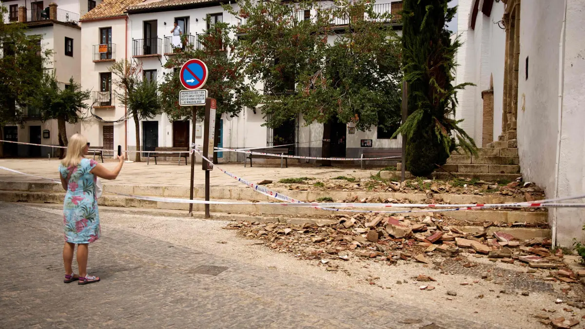 SPAIN-EARTHQUAKE-EMERGENCY: A tourist takes pictures of broken tiles on the floor at the entrance of San Miguel Bajo Church, in El Albayzin barrio of Granada, Andalusia, on August 15, 2026 after an overnight seismic tremor. No casualties or serious and widespread structural damage were reported as a 5-level magnitude earthquake rocks Spain's tourist jewel Granada in the night of August 14-15, 2026. (Photo by Enrique Fajardo / AFP)