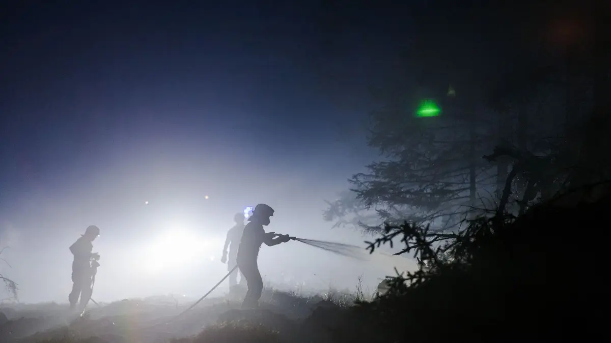 Waldbrand im Hohen Venn: 17.08.2026, Belgien, Sourbrodt: Feuerwehrleute kämpfen in der Dunkelheit im Naturschutzgebiet Hohes Venn weiter gegen einen der größten Waldbrände der belgischen Geschichte. Die Bekämpfung des Brandes ist wegen des torfhaltigen Bodens in dem Naturschutzgebiet besonders schwierig. Foto: Nicolas Lambert/belga/dpa +++ dpa-Bildfunk +++