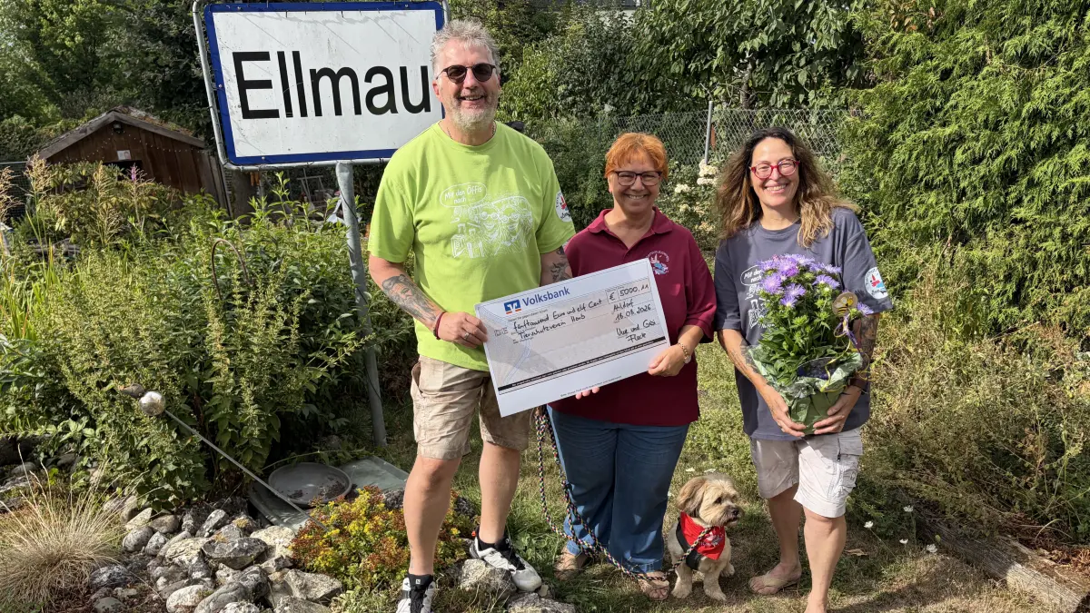 Sogar im Fleckschen Garten in Ahldorf steht ein Ortsschild aus Ellmau (nachgebaut, nicht gestohlen!). Dazu gibt's lachende Gesichter bei der Scheckübergabe: Beatrice Buchmann vom Tierschutzverein, eingerahmt von Gabi und Fleck.