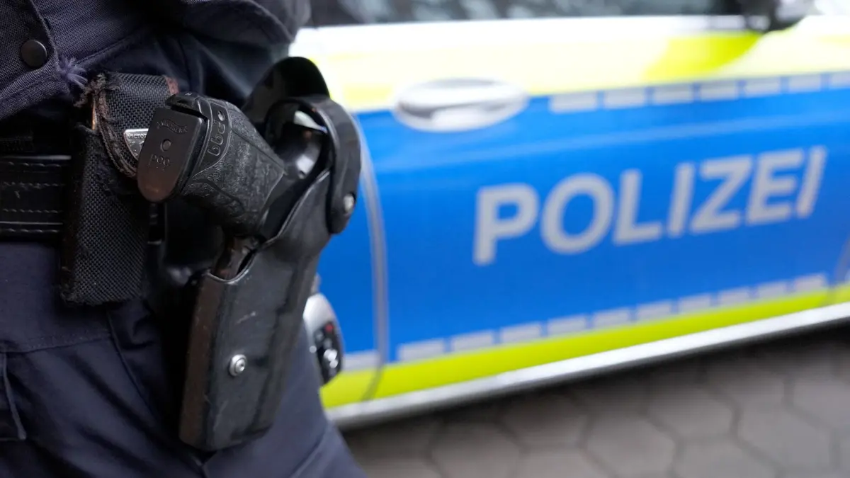 Nach Rockerstreit mit Messern: Polizei durchsucht Wohnungen: ARCHIV - 15.03.2024, Hamburg: Ein Polizist steht vor einem Einsatzfahrzeug der Polizei. (Symbolbild) Knapp zwei Monate nach einer Auseinandersetzung zwischen verfeindeten Rockergruppen mit zwei Schwerverletzten bei einer Party am Lippesee bei Paderborn hat die Polizei drei Tatverdächtige im Visier. (zu dpa: «Nach Rockerstreit mit Messern: Polizei durchsucht Wohnungen») Foto: Marcus Brandt/dpa +++ dpa-Bildfunk +++