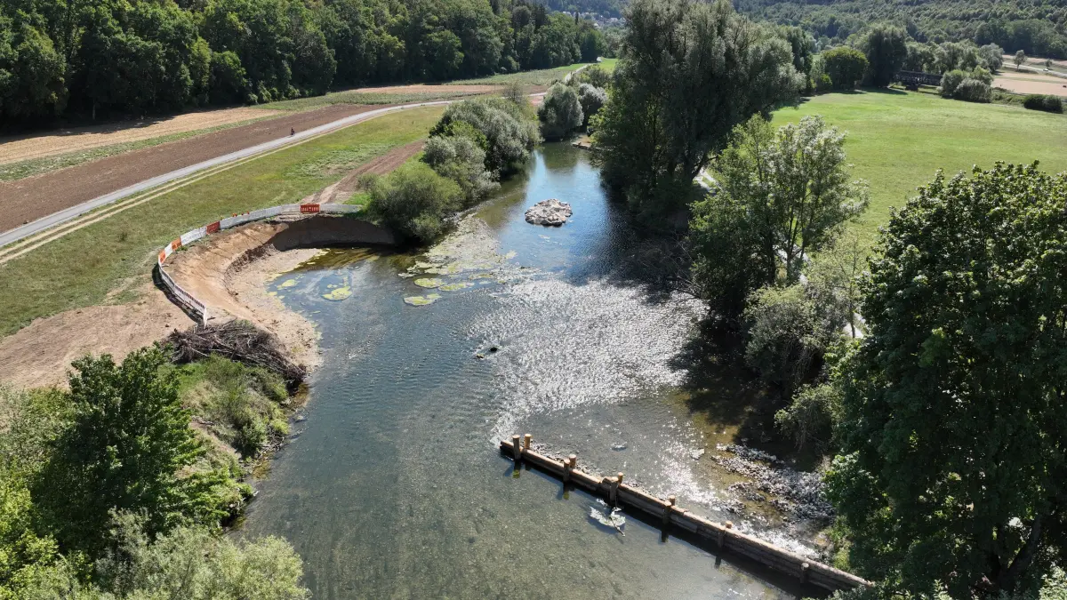 Das erste Teilstück der Neckar-Renaturierung bei Obernau ist fast fertig: Granitsteininseln bringen den Fluss in Wallung. Weiter hinten sieht man (noch von einem Bauzaun umgeben) die aufgeweitete linke (also nördliche) Uferböschung, davor einen mit Stämmen gebauten Strömungslenker.