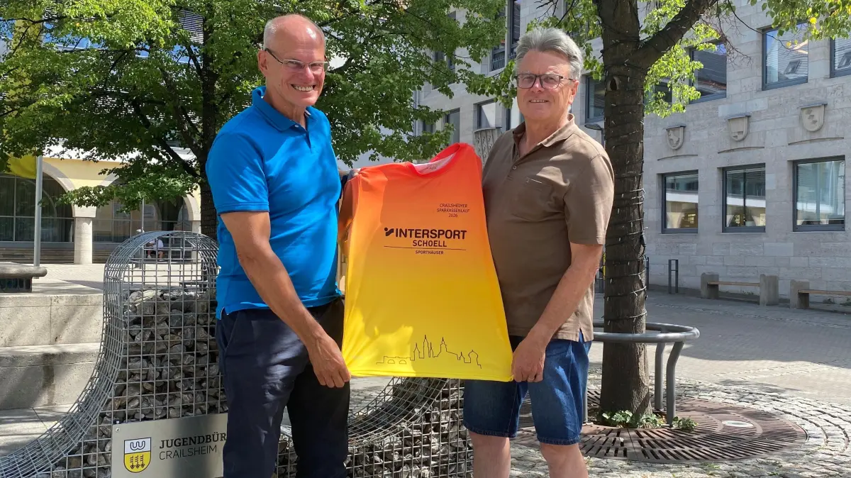 Dieter Brenner, stellvertretender Vorsitzender des TSV Crailsheim, und Helmut Zanzinger, Vorsitzender des Fördervereins Leichtathletik Crailsheim, präsentieren das exklusive Shirt zum 15. Crailsheimer Sparkassenlauf am Marktplatz vor dem Rathaus, wo die Rennen starten.