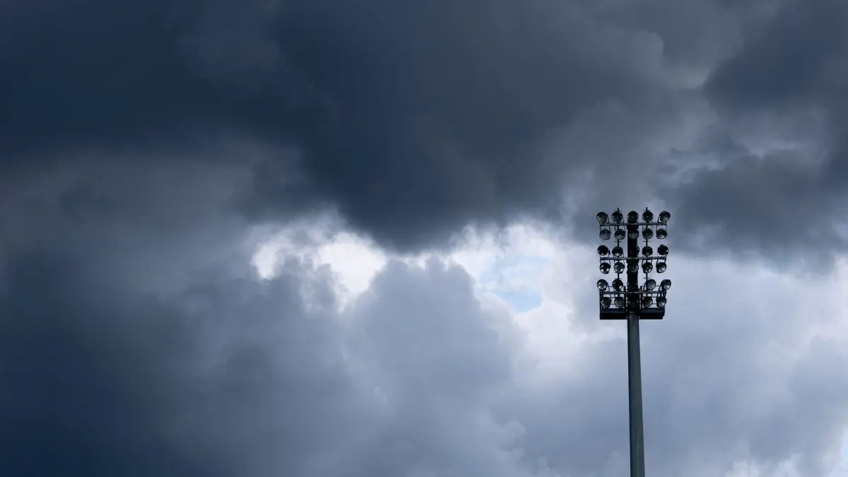 Viktoria Köln - 1. FC Nürnberg: 22.08.2026, Nordrhein-Westfalen, Köln: Fußball, Männer: DFB-Pokal, Viktoria Köln - 1. FC Nürnberg, 1. Runde, Sportanlage Höhenberg. Regenwolken sind hinter einem Flutlichtmast zu sehen. Foto: Fabian Strauch/dpa - WICHTIGER HINWEIS: Gemäß den Vorgaben der Bundesliga bzw. des DFB Deutscher Fußball-Bund ist es untersagt, in dem Stadion und/oder vom Spiel angefertigte Fotoaufnahmen in Form von Sequenzbildern und/oder videoähnlichen Fotostrecken zu verwerten bzw. verwerten zu lassen. +++ dpa-Bildfunk +++