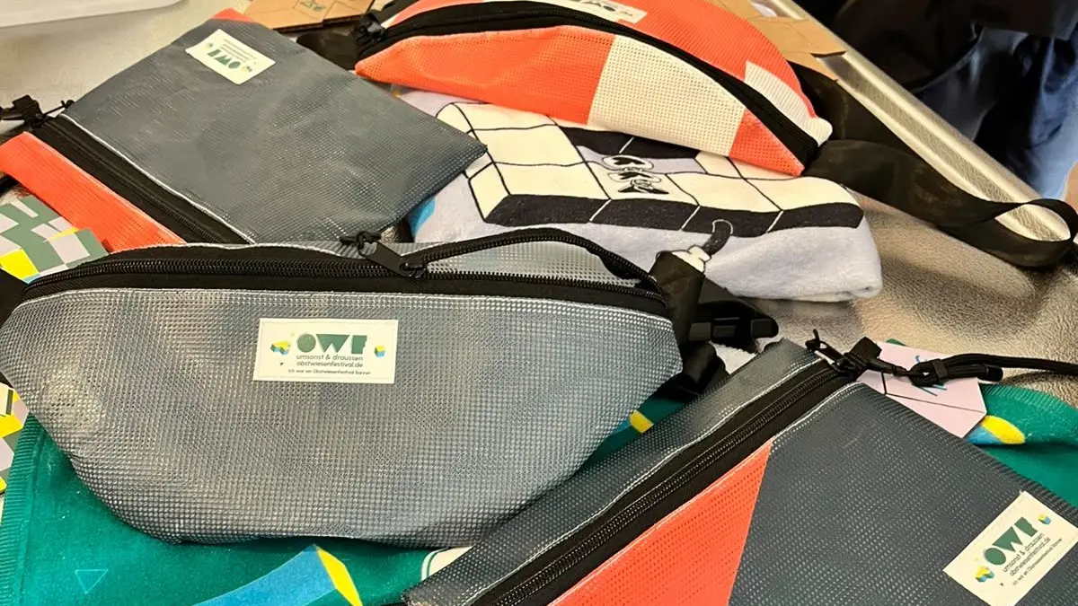 Besonders beliebt bei den Leuten: Bauchtaschen - recycelt aus alter Bühnenplane. Aber auch Festivalbändchen und Socken gehen gut weg. Zu kaufen gibt’s das alles übrigens nur beim Festival selbst. Manches wird dann im nächsten Jahr wieder rausgekramt.