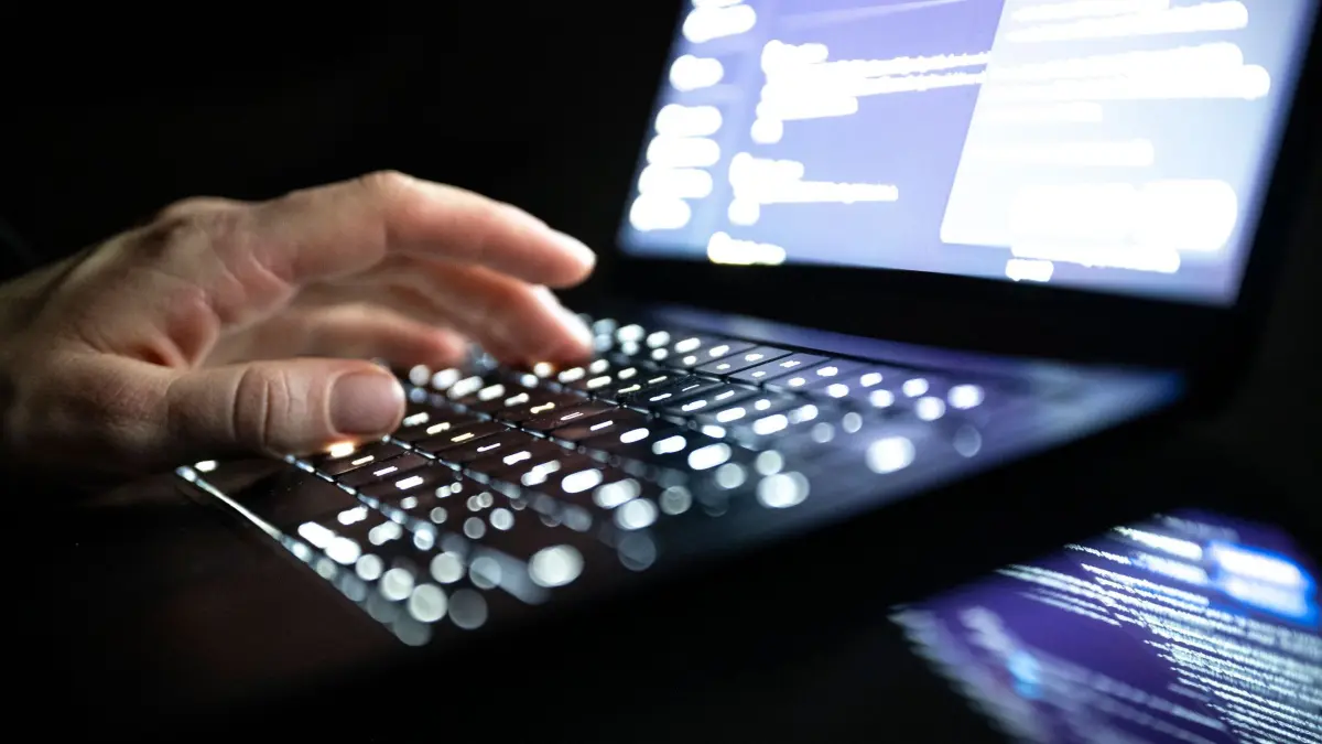 Cyberkriminalität: ILLUSTRATION - 14.12.2025, NA, Berlin: Eine Person tippt mit den Fingern auf einer beleuchteten Laptop-Tastatur. (gestellte Szene) (zu dpa: «Hackerangriff: Staatssekretär fordert mehr Abwehrmaßnahmen») Foto: Philip Dulian/dpa +++ dpa-Bildfunk +++