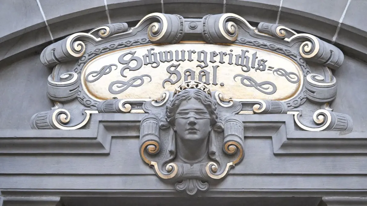 Beginn Prozess gegen Mutter wegen versuchten Mordes: 26.08.2026, Baden-Württemberg, Tübingen: Über dem Eingang zum Gerichtssaal ist die Aufschrift: "Schwurgerichts-Saal" angebracht. Vor dem Gericht beginnt ein Prozess gegen eine 25-jährige Angeklagte, die ihrem intensivmedizinisch in einer Klinik versorgten Sohn, einem sogenannten Frühchen, heimlich eine Überdosis Koffein verabreicht haben soll. Dadurch sei der Säugling für mehrere Tage in einen lebensbedrohlichen Zustand geraten. Die Mutter habe hierdurch für sich selbst Aufmerksamkeit und Zuwendung erlangen wollen. Den Tod ihres Sohnes habe sie billigend in Kauf genommen. Foto: Bernd Weißbrod/dpa +++ dpa-Bildfunk +++