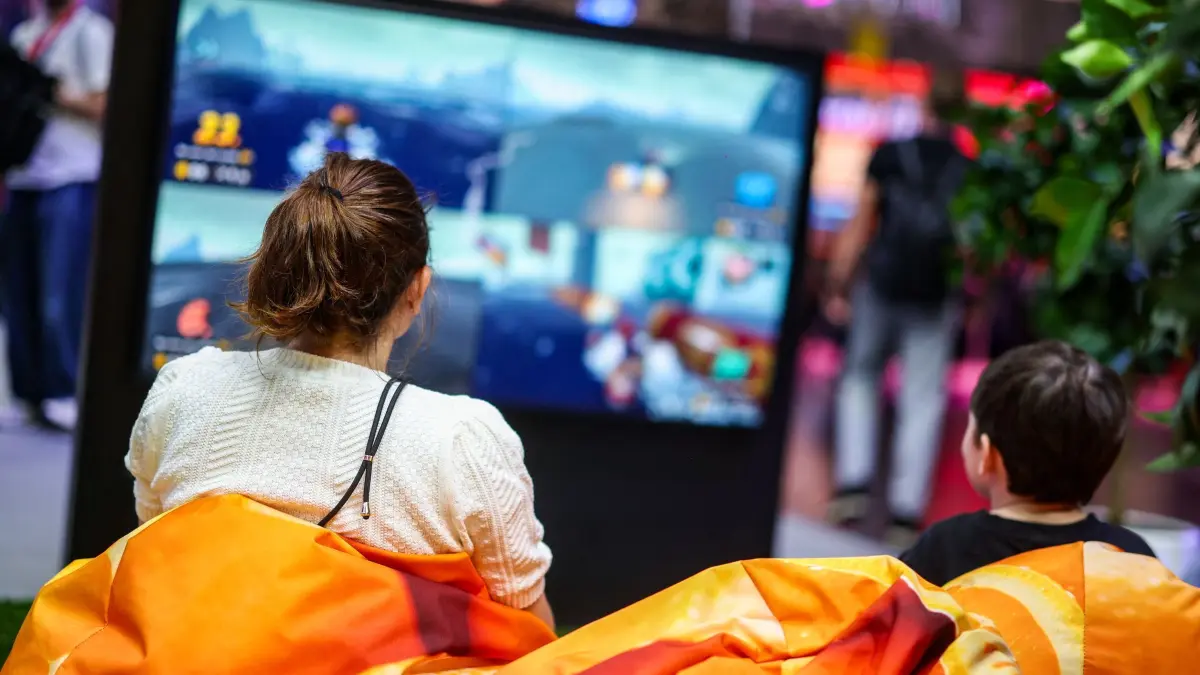 Gamescom 2026: 26.08.2026, Nordrhein-Westfalen, Köln: Zwei Besucher der Messe Gamescom sitzen auf Sitzsäcken vor einem Bildschirm und spielen ein Videospiel. Bei der Messe präsentieren sich so viele Aussteller den Besuchern wie noch nie, sie dauert bis Sonntag. Foto: Christoph Reichwein/dpa +++ dpa-Bildfunk +++