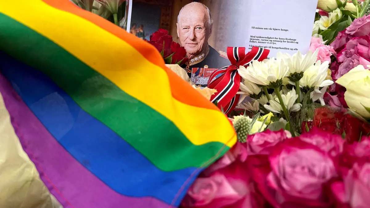 König Harald V. von Norwegen ist tot: 28.08.2026, Norwegen, Oslo: Eine Regenbogenfahne und ein Porträt des verstorbenen Königs Harald V. liegen vor dem Königlichen Schloss Oslo, wo zahlreiche Menschen zusammengekommen sind um zu trauern. Der norwegische König Harald V. ist im Alter von 89 Jahren gestorben. Foto: Julia Wäschenbach/dpa +++ dpa-Bildfunk +++