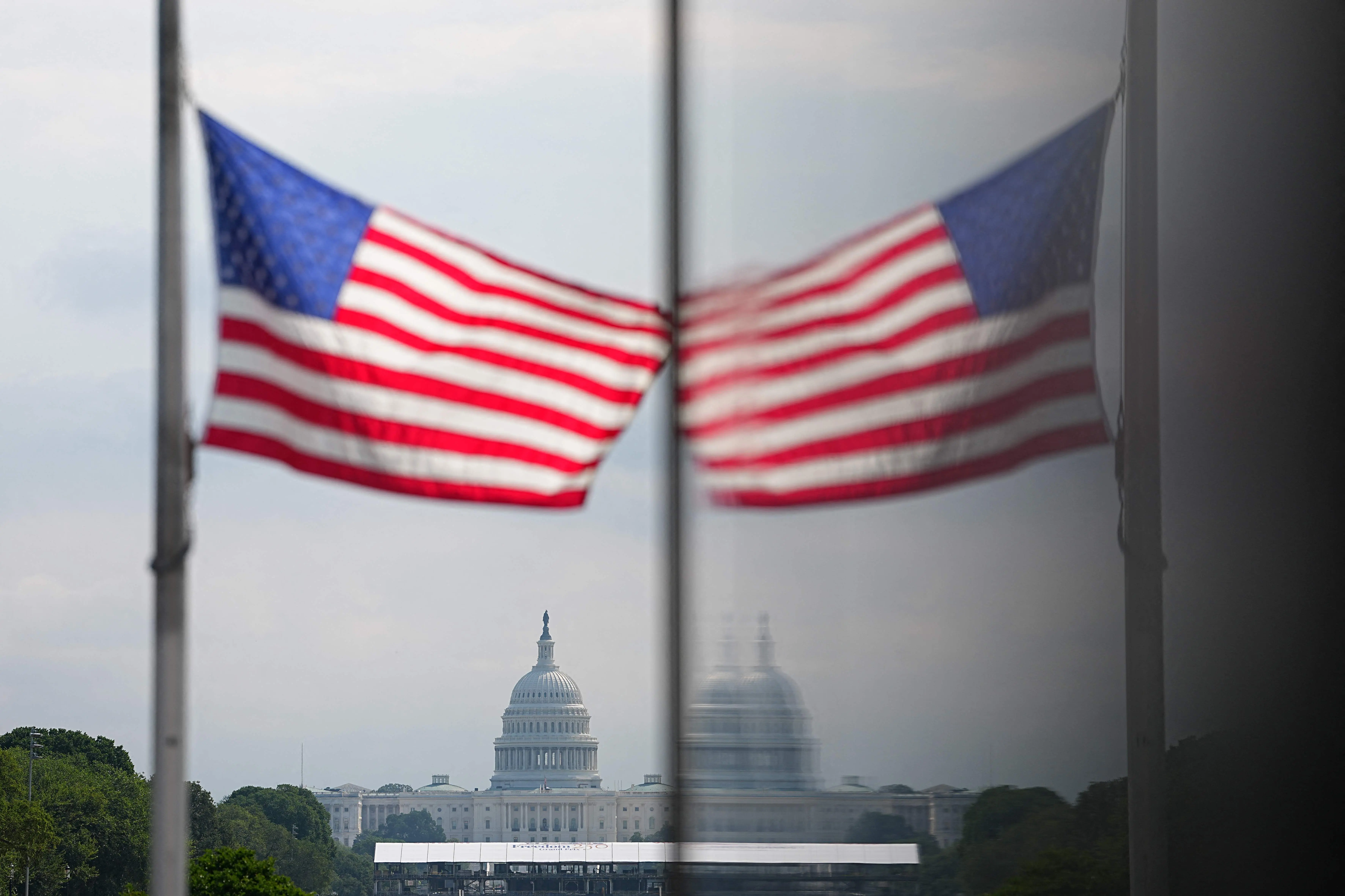 US-POLITICS-VOTING-RIGHTS: A US flag and the done of the US Capitol are reflected in a window during a rally at the Lincoln Memorial in Washington, DC, on August 28, 2026, coinciding with the 63rd anniversary of the 1963 "March on Washington" rally for civil rights. A US federal judge blocked President Donald Trump's executive order on August 27 curbing the use of mail-in ballots, the latest twist in a legal dispute months before November's midterm elections. Trump signed an order in March seeking to restrict mail-in voting ahead of the midterms, but it was immediately met with multiple legal challenges. (Photo by Aaron Schwartz / AFP)