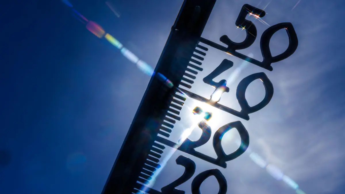 Hitze: ARCHIV - 24.06.2026, Mecklenburg-Vorpommern, Schwerin: Vor einem wolkenlosen blauen Himmel zeigt ein Außenthermometer bereits am Vormittag fast 30 Grad Lufttemperatur an. (zu dpa: «Wetterdienst: Voraussichtlich wärmster Sommer im Saarland») Foto: Jens Büttner/dpa +++ dpa-Bildfunk +++