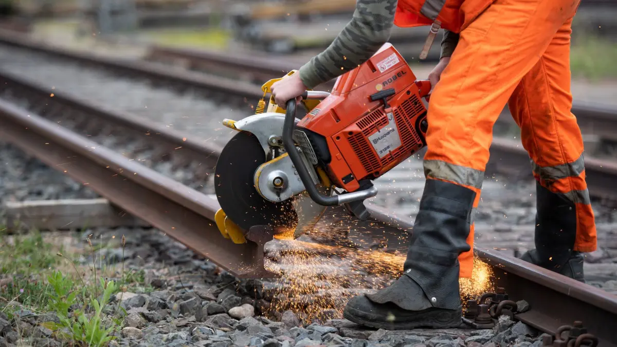 Ausbildung zum Gleisbauer bei der Bahn: ARCHIV - 10.07.2018, Hamburg: Ein Auszubildender der Deutschen Bahn arbeitet auf dem Gelände einer Ausbildungswerkstatt mit einem Schienen-Trennschleifgerät an einer Schiene. (zu dpa: «Neues Ausbildungszentrum der Bahn startet in der Oberlausitz») Foto: Daniel Reinhardt/dpa +++ dpa-Bildfunk +++