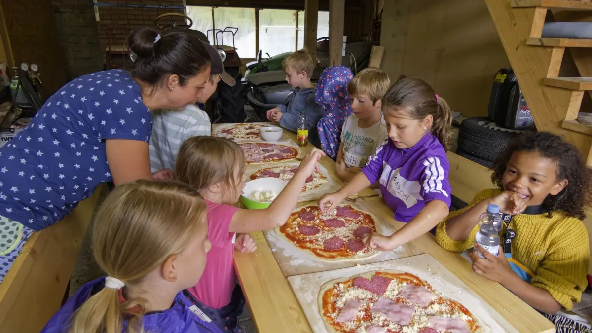 Katrin Kugler gibt den Kindern Tipps für das Belegen der Pizza.