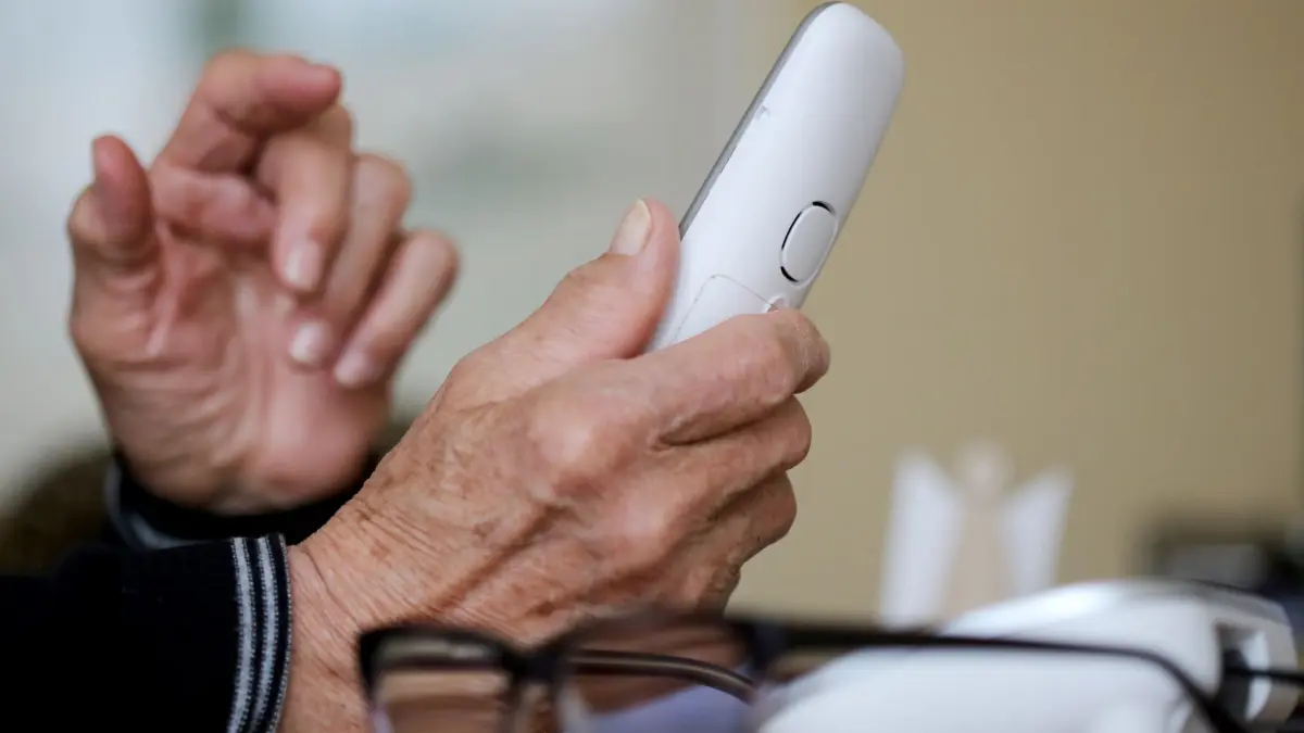 Rentner hält Telefon in der Hand: ARCHIV - 10.03.2021, Nordrhein-Westfalen, Essen: Ein Senior hält einen Telefonhörer in der Hand. (zu dpa: «Schockanrufer bringen 92-Jährigen um fünfstelligen Betrag») Foto: Roland Weihrauch/dpa +++ dpa-Bildfunk +++