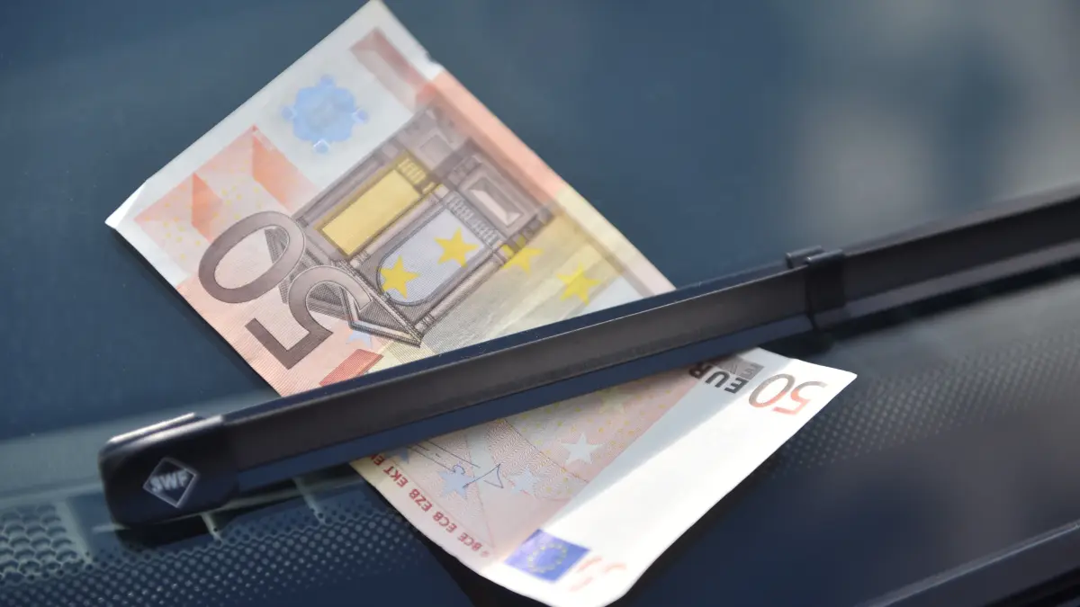 Ein 50 Euro Schein klemmt unter einem Scheibenwischer eines Autos. (Symbolbild)