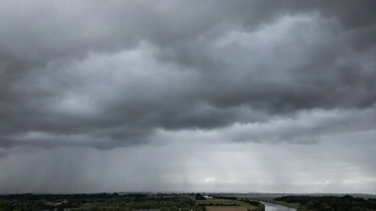 Regenwolken über der Weser: 13.09.2026, Nordrhein-Westfalen, Buchholz: Dunkle Regenwolken ziehen über den Ort an der Weser (Luftaufnahme mit einer Drohne). Foto: Boris Roessler/dpa +++ dpa-Bildfunk +++
