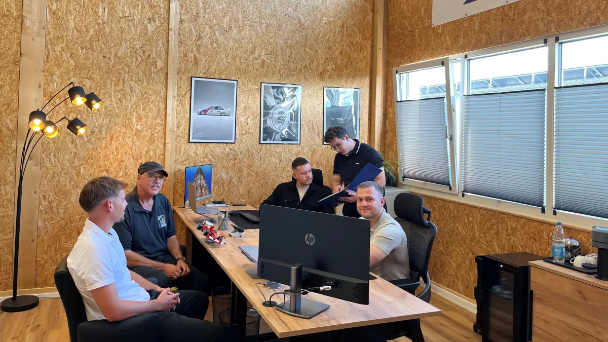 (Hinter dem Tisch, von hinten nach vorne) Leon Hammer, Daniel Mittelstädt und David Sydlo gründen in Eutingen das Start-up Automobilzentrum Neckar-Gäu. Andreas Piscol (vor dem Tisch, mit Kappe) ist Vermieter des Gewerbeparks, indem sie unterkommen. Die Idee, so einen Gewerbepark in Eutingen zu stationieren, hatte sein Sohn Moritz Sowinsky (vor dem Tisch vorne).