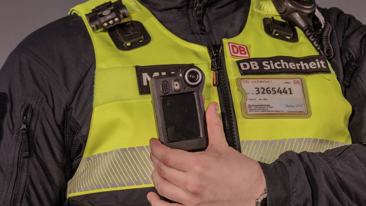 Deutsche Bahn lädt zu Sicherheitsgipfel ein: ARCHIV - 13.02.2026, NA, Berlin: Ein Mitarbeiter der DB Sicherheit zeigt eine Bodycam nach einer Pressekonferenz bei dem Sicherheitsgipfel bei der Deutschen Bahn. (zu dpa: «Gedenken auf Gleis 1») Foto: Carsten Koall/dpa +++ dpa-Bildfunk +++