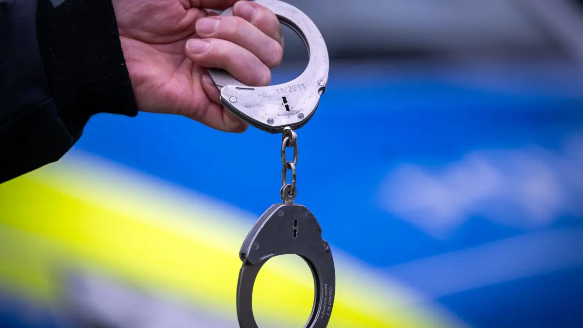 Handschellen Symbolbild: Ein Polizist hält während einer Verkehrskontrolle an der Berliner Straße ein Paar Handschellen. (zu dpa: «Schreckschuss aus nächster Nähe ins Gesicht – Mann in Haft»)