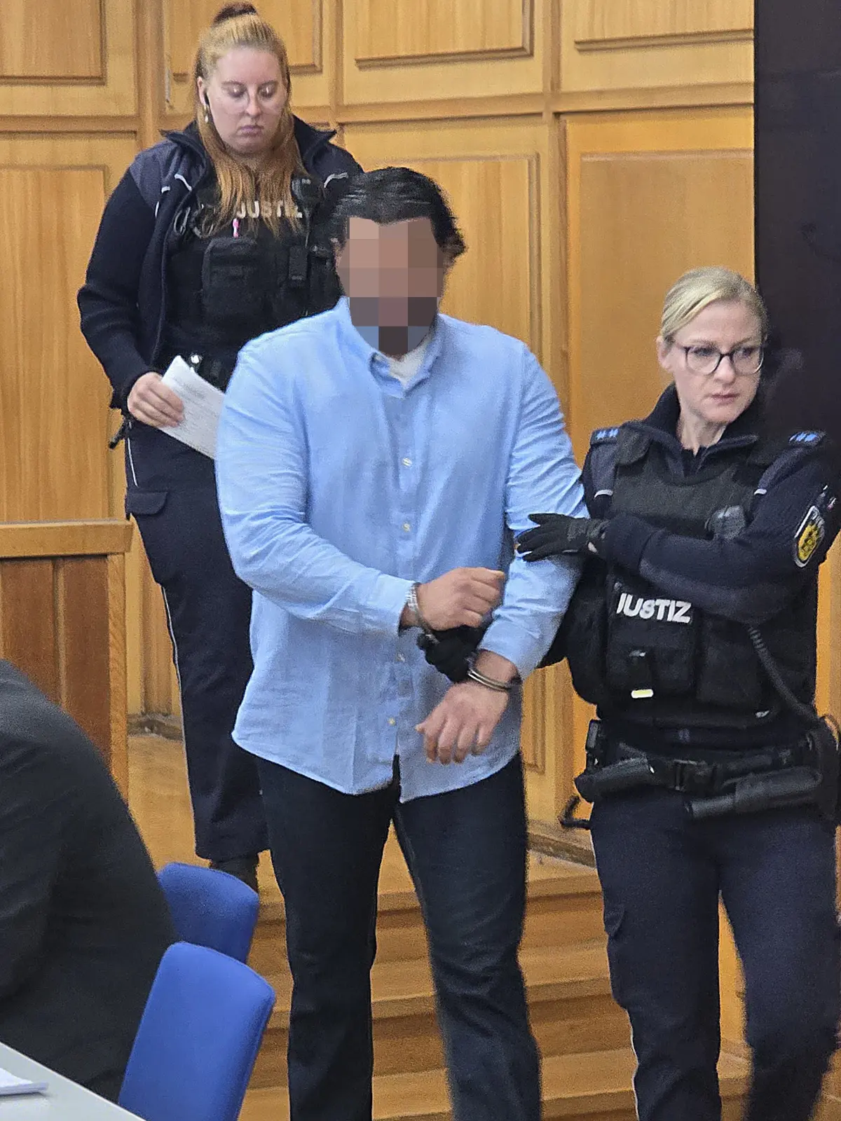 Zwei Justizvollzugsbeamtinnen bringen den Angeklagten am ersten Prozesstag aus der Untersuchungshaft in den Saal.