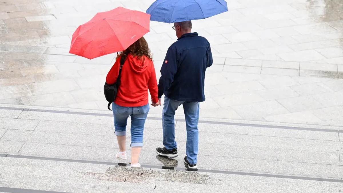 Wetter in Nordrhein-Westfalen: 20.09.2026, Nordrhein-Westfalen, Köln: Spaziergänger schützen sich auf dem Bahnhofsvorplatz mit Schirmen vor dem Regen. Die Meteorologen sagen für die nächste Woche wechselhaftes Wetter mit Regen und Temperaturen um die 20 Grad voraus. Foto: Roberto Pfeil/dpa +++ dpa-Bildfunk +++