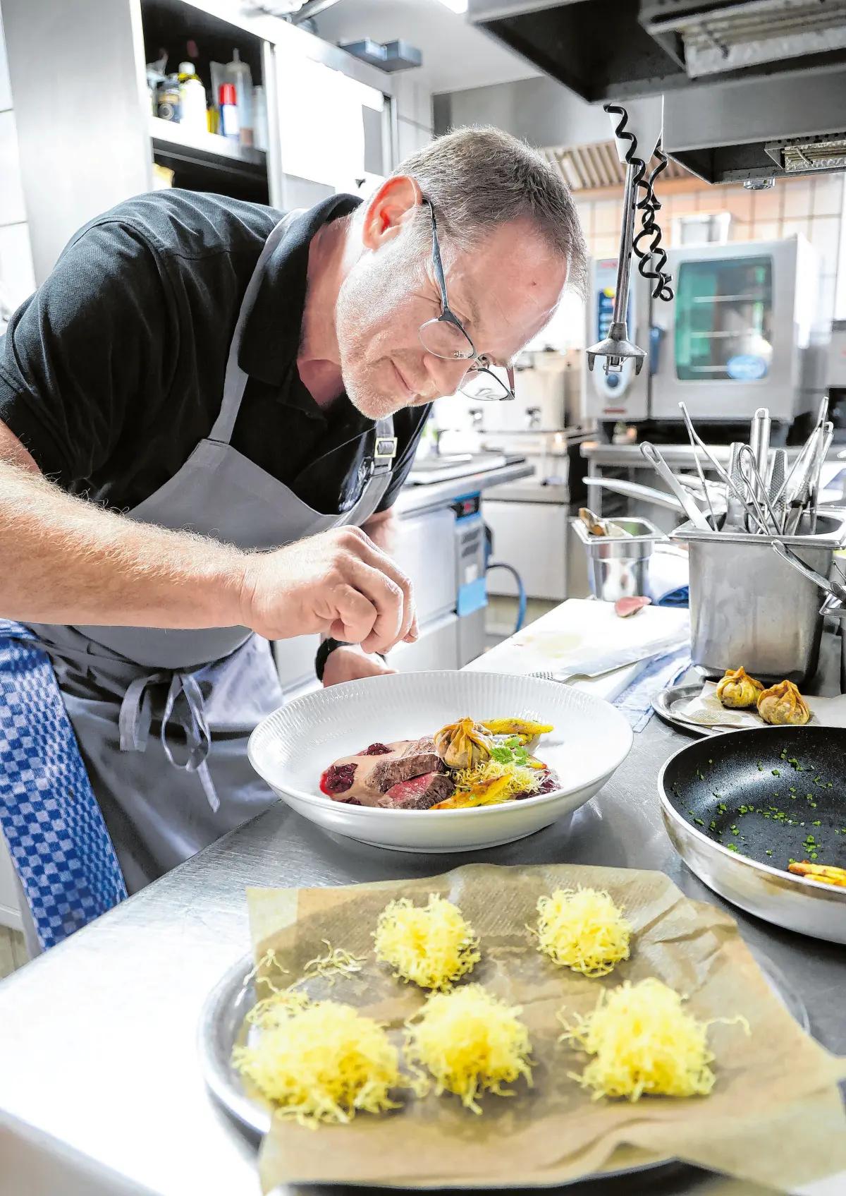 Dritter Gang: Der Küchenchef richtet das Zweierlei von der Sulzbacher Rehkeule in Tonkabohnenjus auf Pastinakenpüree mit Schupfnudeln und (im Vordergrund) Selleriestroh an.